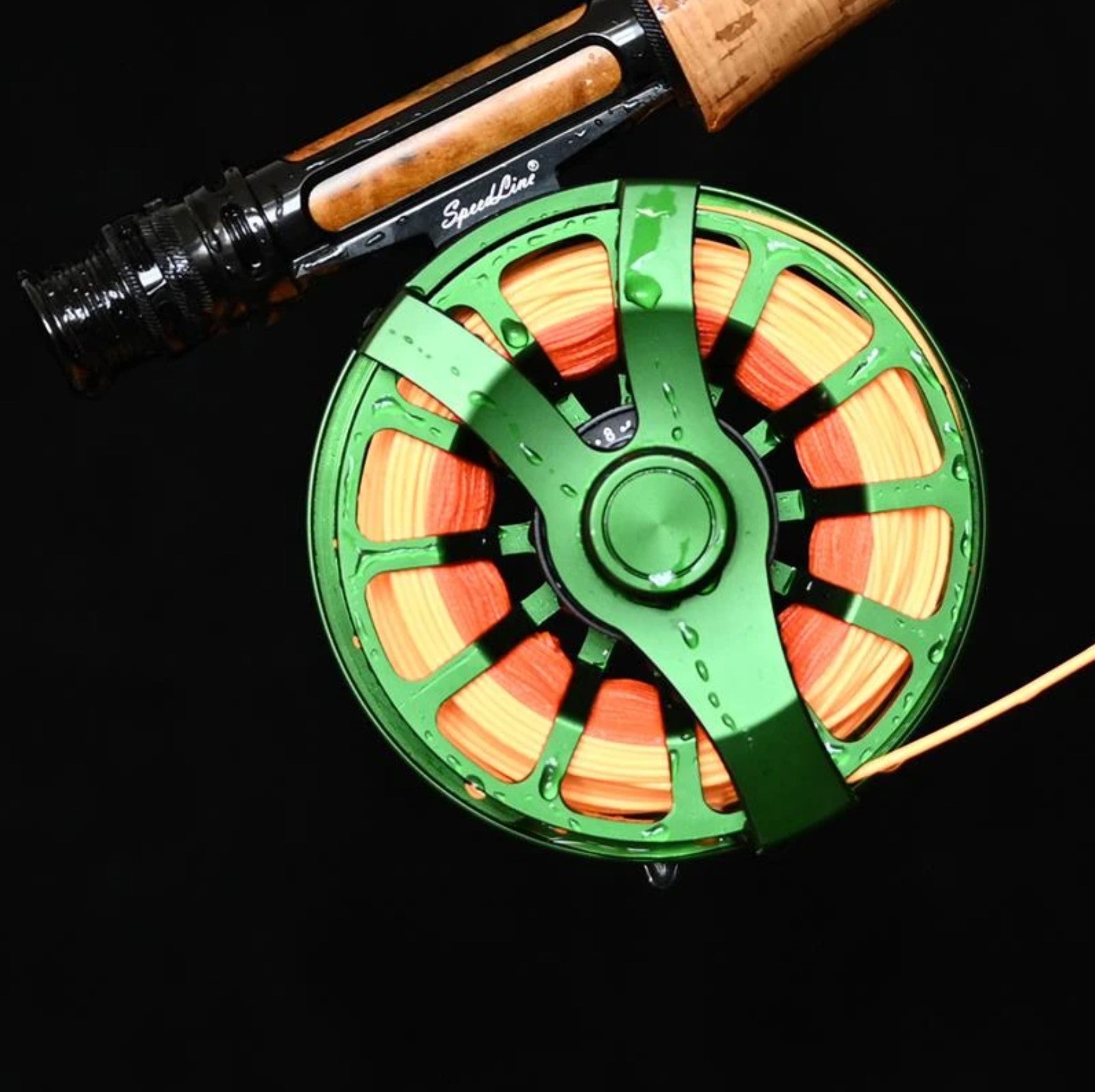 Green alloy fly reel attached to fly rod